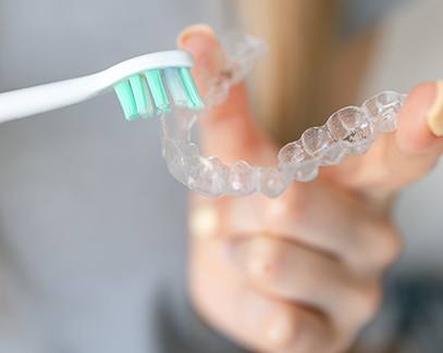Woman using toothbrush to clean aligner