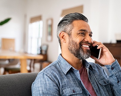 Man in blue shirt smiling while talking on phone