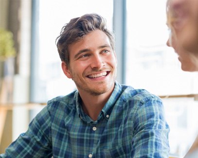 Man smiling at friends while talking in restaurant