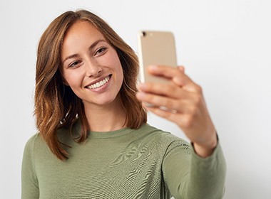 Woman in green shirt smiling while taking a selfie