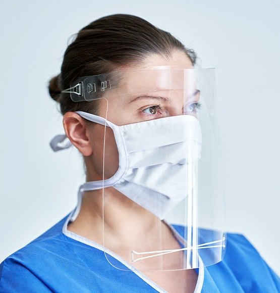 Dental team member wearing face mask and plastic shield