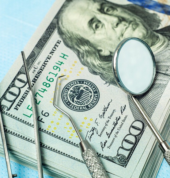 Money and dental tools symbolizing the cost of cosmetic dentistry in Tucson 