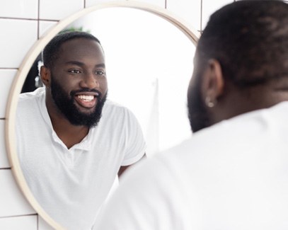 Man in white shirt smiling and looking in a mirror 