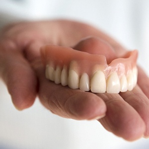 person holding a denture in their hand