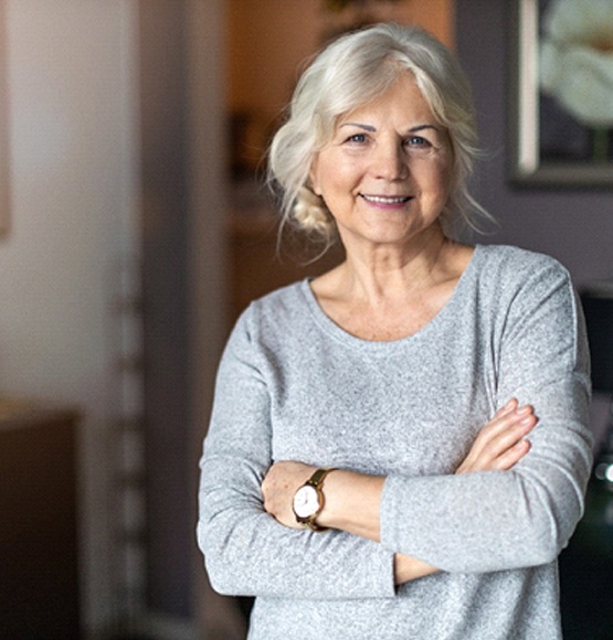 Older woman smiling with her arms crossed in grey shirt