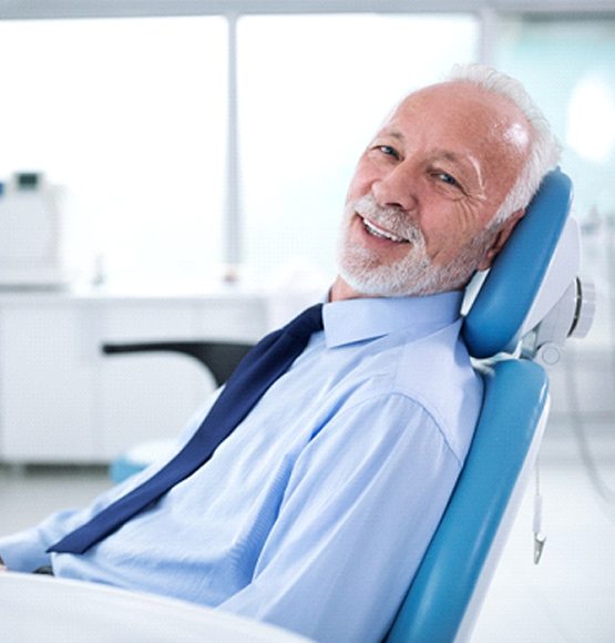 Man with white hair and beard smiling in dental chair
