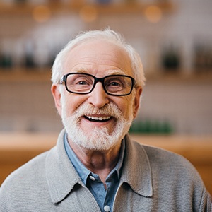 An older man with glasses sitting and smiling