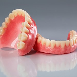 Upper and lower full dentures in Tucson, AZ on a reflective table