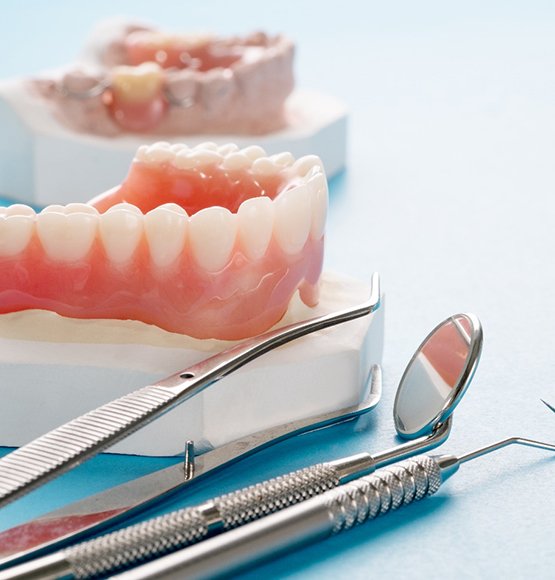 a model of dentures next to dental tools