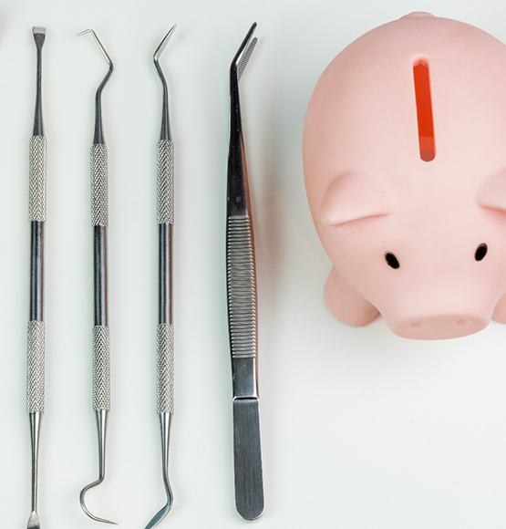 Piggy bank next to dental instruments representing cost of emergency dentistry in Tucson, AZ