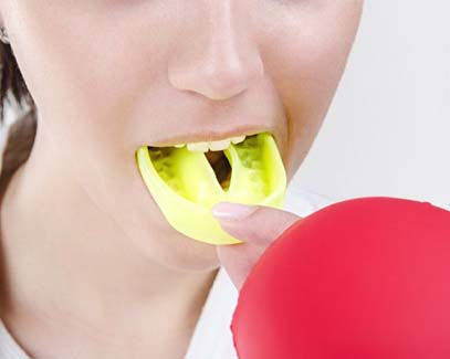 person putting a yellow mouthguard into their mouth