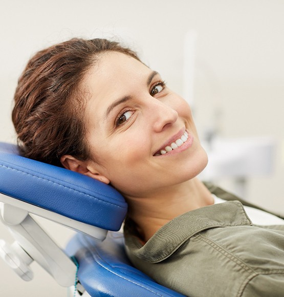 Female dental patient leaning back in chair and smiling
