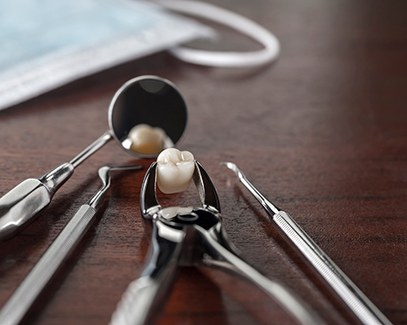 Close-up of forceps holding tooth after tooth extraction in Tucson, AZ