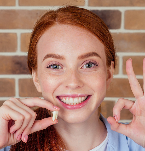 a woman in Tucson holding her tooth after an extraction 