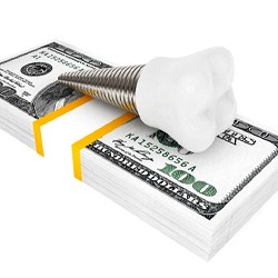 Implant on money stack representing cost of dental implants in Tucson