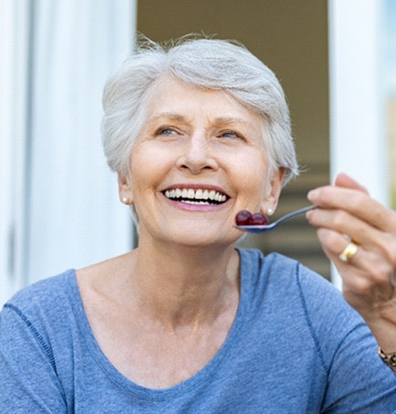 Woman eating with implant dentures in Tucson