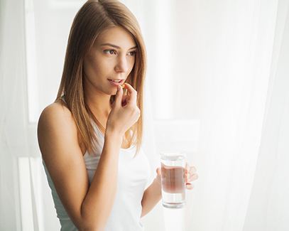 woman taking medication for dental implant post-op instructions in Tucson