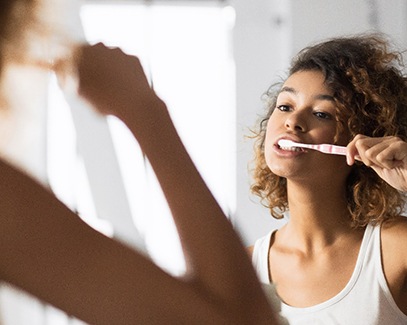 woman brushing teeth for dental implant post-op instructions in Tucson