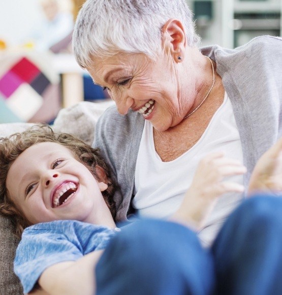 Older woman and child laughing after dental implant tooth replacement