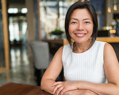 Smiling woman in a café with dental implants in Tucson