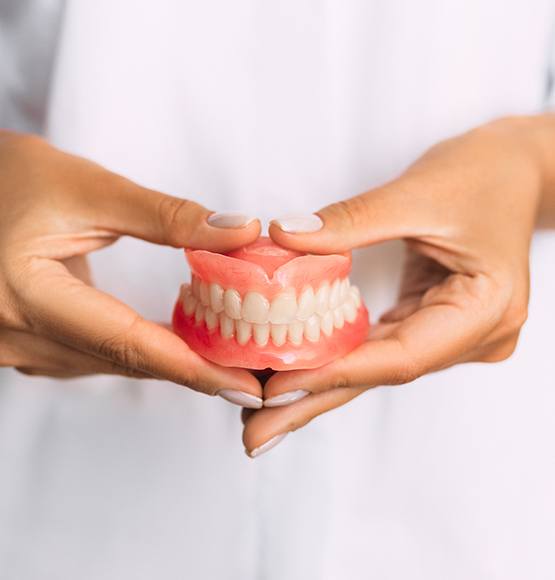 Dentist holding full upper and lower dentures