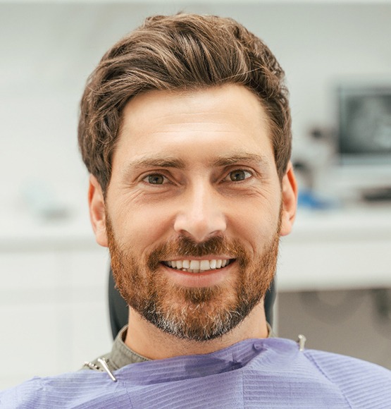 Bearded man sitting in dental chair and smiling