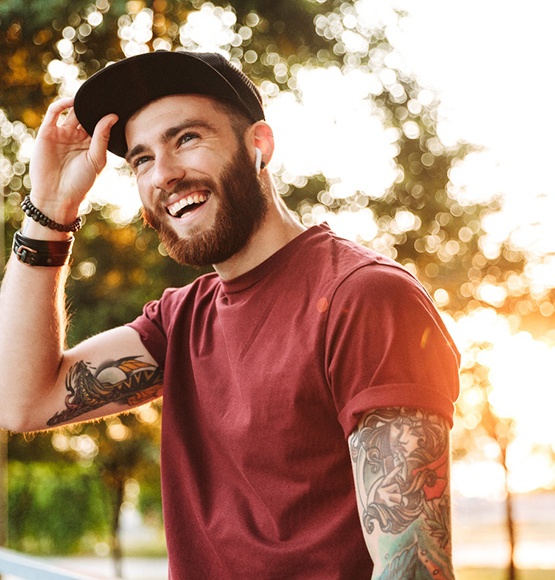 Man with hat and red shirt walking and smiling outside