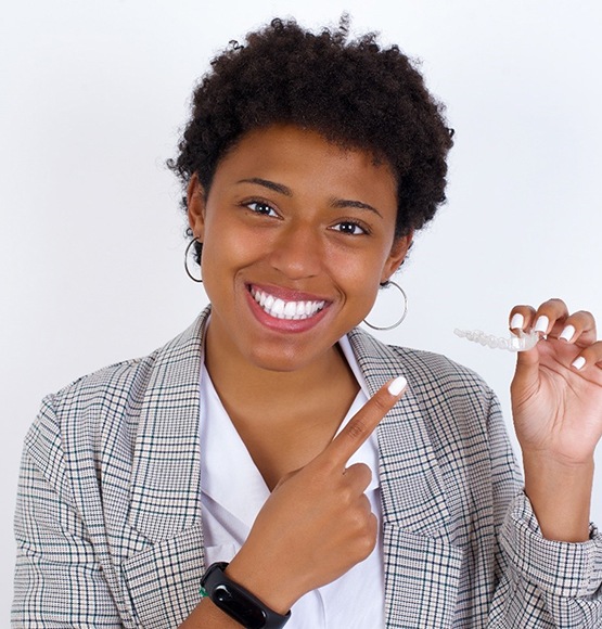 woman smiling holding SureSmile clear aligner in Tucson