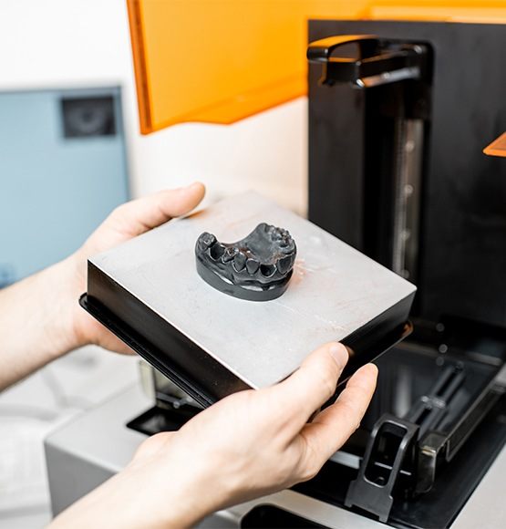 Dental team member using 3 D printer to create a smile model