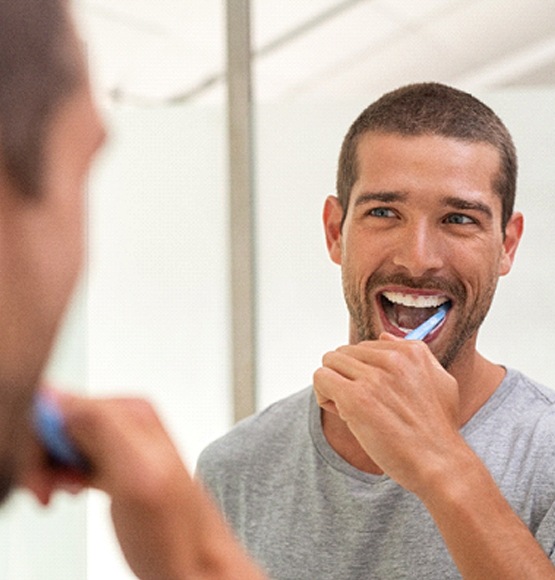 Closeup of man smiling while brushing his teeth