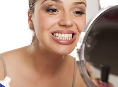 woman sadly checking smile in mirror