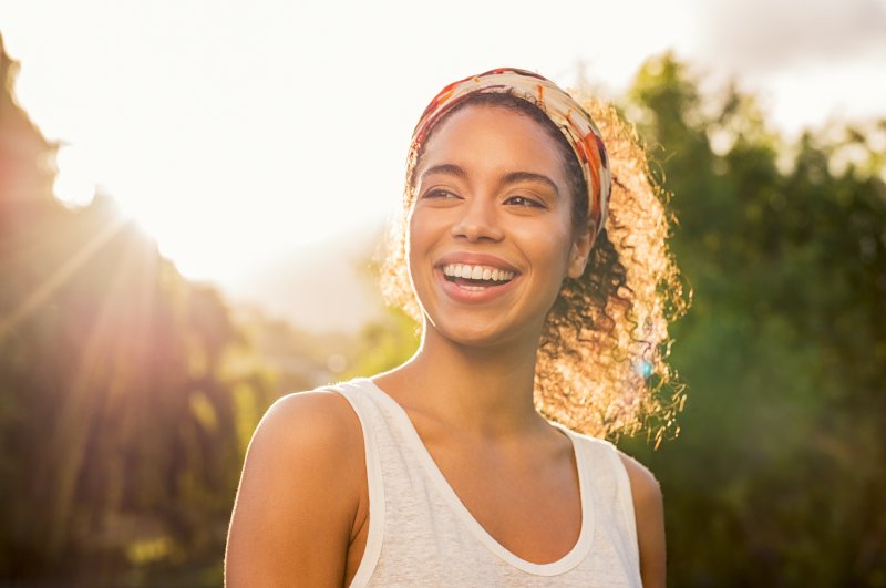 Woman with headband smiling outdoors in the sun