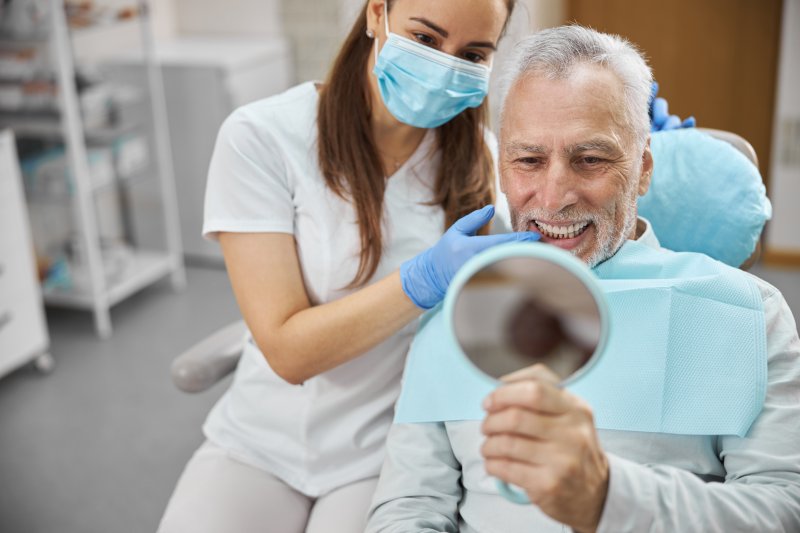 An older man admiring his dental implants