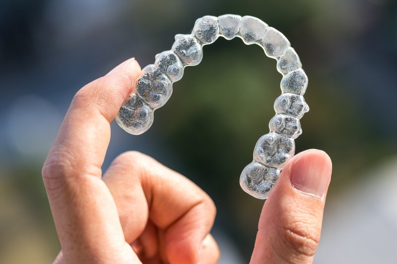 person holding an Invisalign aligner