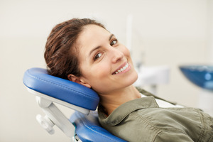 Female patient sitting back in dental chair and smiling