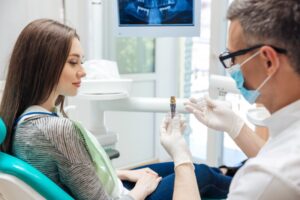 Dentist showing a patient a model of a dental implant crown